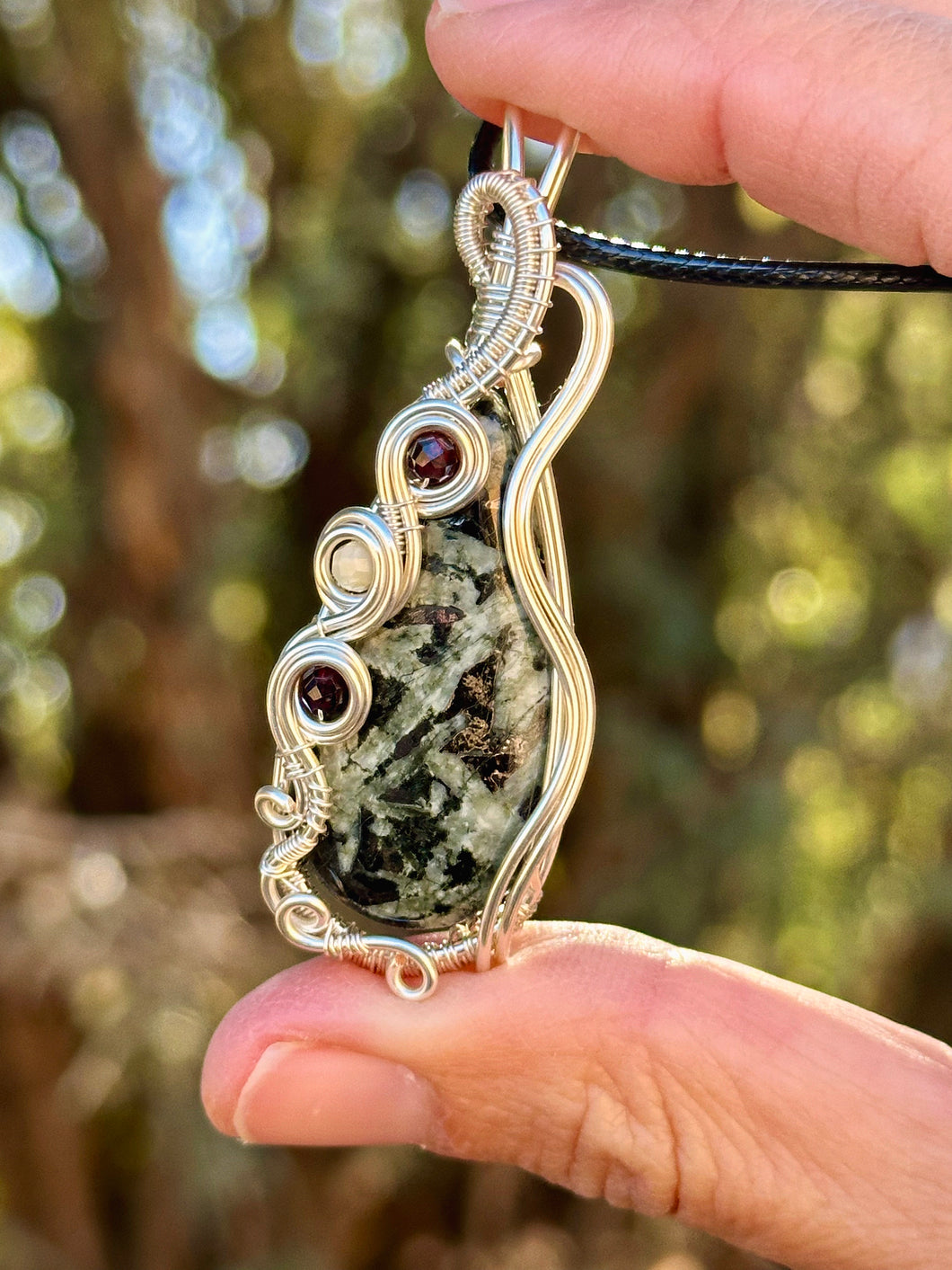 Chrysanthemum with garnet + moonstone inclusions   wire wrapped pendent