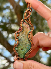 Load image into Gallery viewer, artisan cab (positive rock) rainbow fossilized palm root with garnet, carnelian, blue topaz, peridot gem accent wire wrapped pendant necklace
